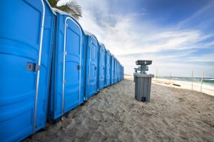 line of porta potties in the beach with a hand washing station